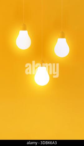 Three glowing light bulbs creating bright light and casting a vibrant glow on a plain yellow background. Representing creativity and ideas Stock Photo