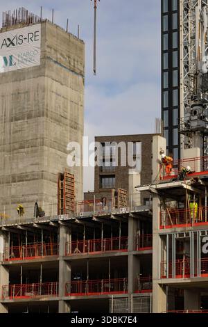 Manchester, uk, January 19th 2025 Active construction scene featuring a tall crane, scaffolding, and workers in safety gear on multiple levels of a co Stock Photo