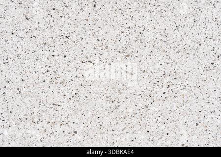High-resolution quartz or terrazzo texture background showing a polished white surface embedded with tiny gray, brown, and black mineral pebbles Stock Photo