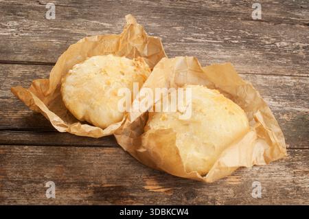 Homemade sourdough rolls wrapped in baking paper on a dark wood surface Stock Photo