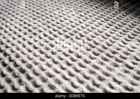 Macro close-up: beige waffle fabric texture. Soft, cozy, and versatile. Perfect for home decor, crafts, and fashion accessories. Stock Photo