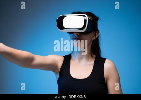 Female user interacting with VR interface while wearing headset in futuristic digital reality scene Stock Photo