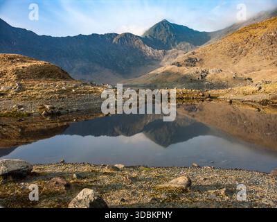 The 1085m summit of Yr Wyddfa (Mt Snowdon), the highest mountain in Wales, reflected in the still water of Llyn Llydaw lake Stock Photo