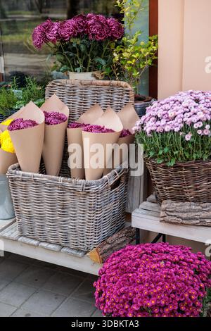 Eco friendly flower bouquets in craft paper, sustainable floristry and natural decoration concept, autumn chrysanthemums in wicker baskets outside flo Stock Photo