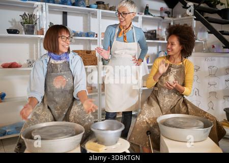 Smiling women having fun together making pot in studio on pottery workshop. .  Creative, scluptor, hobby ,activities concept Stock Photo