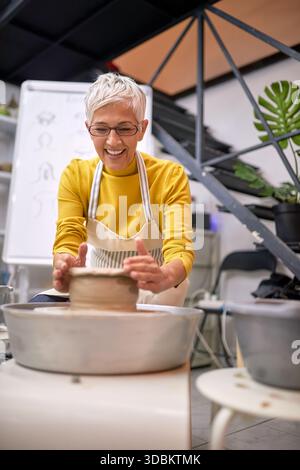 smiling Female Sculptor  shape clay on rotate machine in studio. Modeling ,project.  Creative, hobby ,workshop  concept Stock Photo