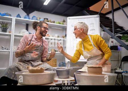 smiling Artists having fun while making pots from clay in studio. . Modeling ,project.  Creative, hobby ,workshop  concept Stock Photo