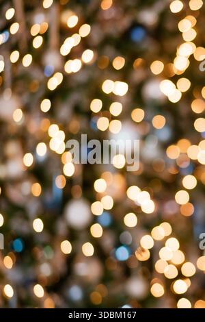 Golden bokeh decorative light on the Christmas tree. The texture is a circular bokeh created from blurry orange light bulbs tangled in the wood. || Model released Stock Photo