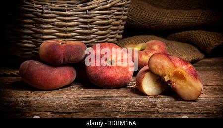 Donut Peaches also known as Saturn peaches on a rustic wooden table. Stock Photo