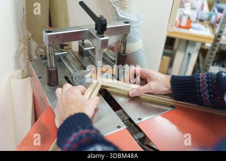 Hands of a craftsman using a professional underpinning machine to join a wooden picture frame. High quality photo Stock Photo