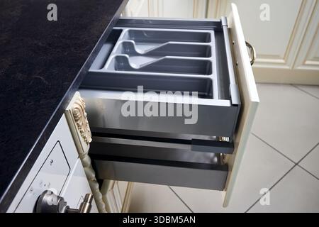 Solutions for placing utensils in classic kitchen - horizontal sliding pull out drawer shelves storage in a cupboard for kitchenware cookware under st Stock Photo