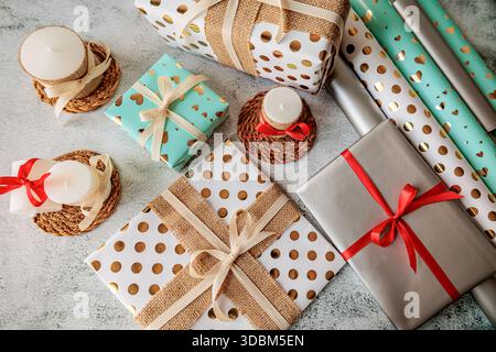 Festive flat lay with gifts and decorative candles on straw coasters. Handmade wrapping and cozy rustic aesthetic for winter celebrations Stock Photo