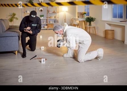 Forensic expert taking photos of knife with blood doing murder investigation with police officer Stock Photo