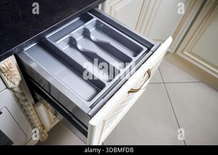 Solutions for placing utensils in classic kitchen - horizontal sliding pull out drawer shelves storage in a cupboard for kitchenware cookware under st Stock Photo