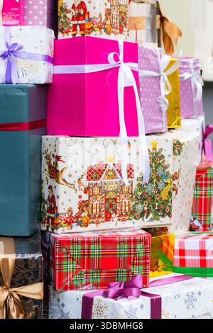 Stack of Colorful Christmas Gift Boxes Wrapped in Festive Paper with Purple Ribbon Stock Photo