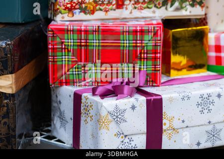 Stack of Colorful Christmas Gift Boxes Wrapped in Festive Paper with Purple Ribbon Stock Photo