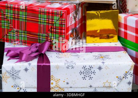 Stack of Colorful Christmas Gift Boxes Wrapped in Festive Paper with Purple Ribbon Stock Photo