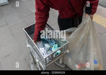 person sorting and collecting waste outdoors into clear plastic bag, Istanbul, Turkey Stock Photo