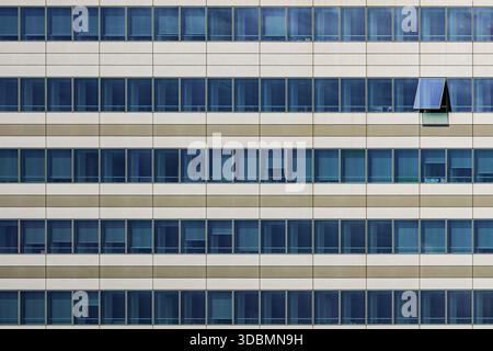 Milan, Italy, Vittoria Assicurazioni office building, Facade with horizontal beige and white bands, rows of blue windows, one window open in the uniform grid, located in Gino Valle Square, Portello district Stock Photo