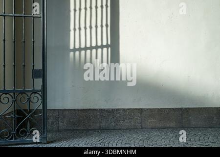 Munich, Germany, wrought iron gate casting geometric shadows on white wall. Stock Photo