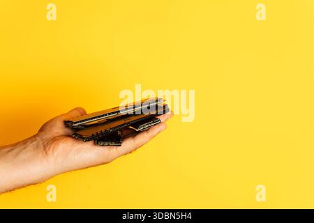 Hand holding multiple DDR RAM sticks on bright yellow background with copy space Stock Photo