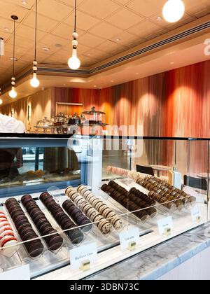 Assorted macarons and pastries displayed behind glass in a warm, inviting New Orleans cafe. Stock Photo