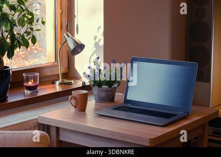 Home working place with laptop. Cozy home interior in the warm window light. Stock Photo