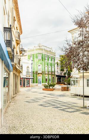 Charming street scene in Lagos, Algarve, Portugal, featuring traditional Portuguese architecture with a distinctive green azulejos tiled building. Stock Photo