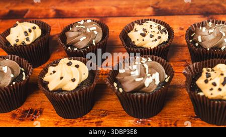 Assorted chocolate and caramel mini cupcakes beautifully arranged on a wooden board. Moist, bite-sized desserts perfect for parties and sweet indulgen Stock Photo