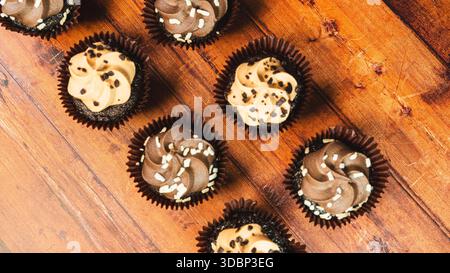 Assorted chocolate and caramel mini cupcakes beautifully arranged on a wooden board. Moist, bite-sized desserts perfect for parties and sweet indulgen Stock Photo