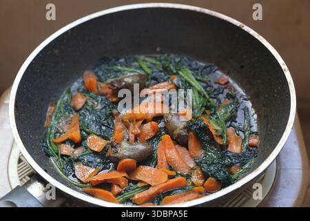 Fried eggs with spinach and pumpkin, in a frying pan. Stock Photo