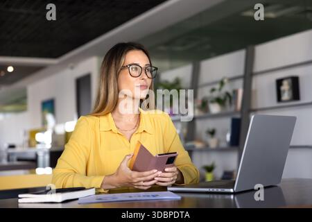 Serious pensive young professional woman in glasses using smartphone Stock Photo