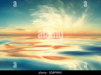 A peaceful seascape at sunrise or sunset with rippling water reflecting a cloudy sky illuminated by brilliant colours, creating a tranquil atmosphere Stock Photo
