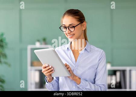 Confident Business Lady Reading Documents on Digital Tablet in Modern Office Space Stock Photo