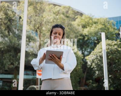 Freelance professional standing outdoors and working on a tablet. Stock Photo