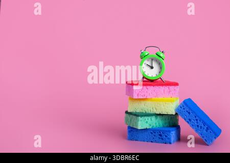 sponges multi colored with alarm clock on isolated pink background cleaning concept Stock Photo
