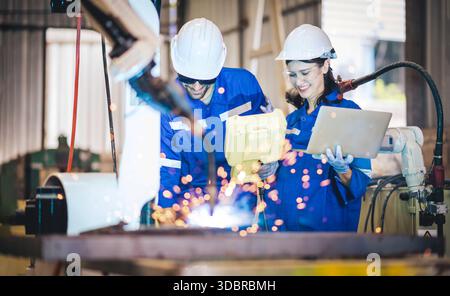 Engineers team mechanic using computer controller Robotic arm for welding steel in steel factory workshop. Industry robot programming software for aut Stock Photo