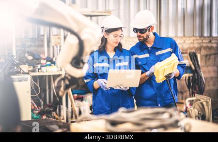 Engineers team mechanic using computer controller Robotic arm for welding steel in steel factory workshop. Industry robot programming software for aut Stock Photo