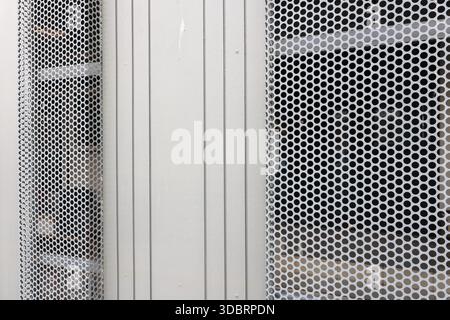 Close up view of abstract white perforated metal texture pattern with holes and vertical lines showing industrial clean solid and strong feeling of st Stock Photo