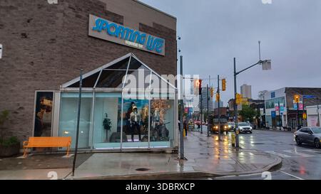 Toronto, ON, Canada - August 31, 2025: The Sporting Life storefront is visible in an urban setting on a cloudy day, with a red traffic light and the Y Stock Photo