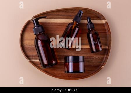 Amber glass bottles and jar for natural skincare products on wooden tray Stock Photo