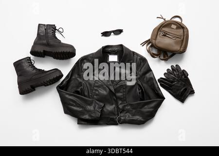 Stylish black leather jacket with boots, backpack, gloves and sunglasses isolated on white background Stock Photo