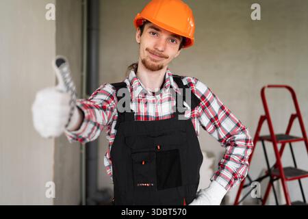 male laborer, builder or repairman ready for repairing or building with thumbs up for agreement, motivation or thank you works at construction site. c Stock Photo