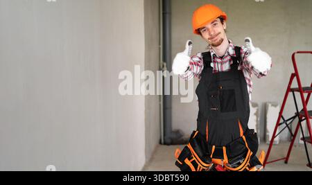 Handyman wearing tool belt with thumbs up Stock Photo - Alamy