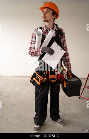 male worker or engineer in hard hat and tool belt in new modern house. copy space Stock Photo