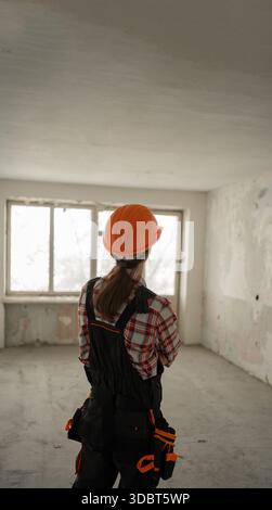 Rear view of Construction worker wearing hard hat performing renovation tasks in apartment. copy space Stock Photo