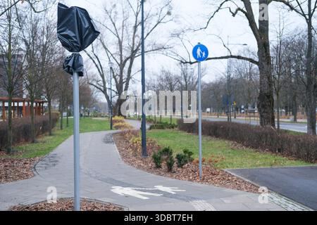 Low-angle outdoor view of red and white Canada flag on metal pole, fabric texture visible, mounted streetlight and dome security camera. Stock Photo
