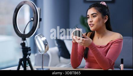 Ring light, woman and influencer with makeup brush for live streaming, beauty or tutorial. Cosmetics, foundation and person recording video on phone Stock Photo