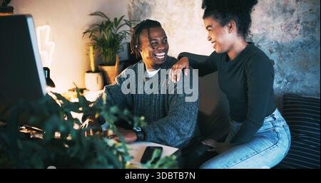 Night, couple and smile in home with computer for planning vacation, trip research and bonding together. Evening, woman and man in relationship with Stock Photo