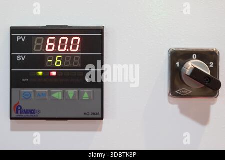 { "description": "A close-up of a digital control panel displaying red numerical values next to a black three-position rotary selector switch on a whi Stock Photo